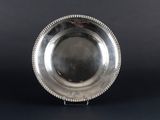 silver plate with beaded edge on stand on black background