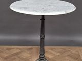 une table au plateau en marbre blanc posée sur un parquet