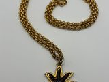 a gold chain with a black flower pendant on it