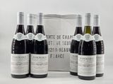 four bottles of wine are lined up in front of a bag