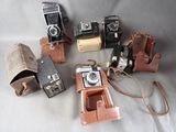 several old cameras are lined up in a row on a white surface