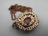 gold plated necklace with a pink stone center surrounded by a chain