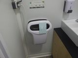 un urinoir blanc dans un coin des toilettes, sur lequel est collée une note