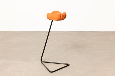 une petite chaise orange posée sur un pied en métal