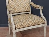 une vieille chaise dont le dossier et les accoudoirs sont recouverts d'un tissu à motifs