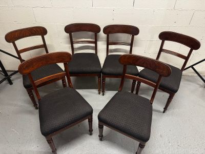 six chaises et un tabouret sont disposés en cercle dans une pièce