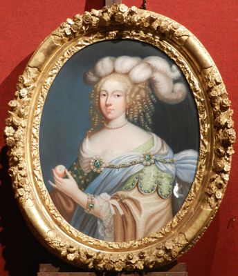 un tableau représentant une femme, dans un cadre doré, accroché à un mur rouge