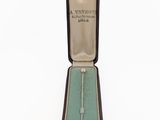 a small box with a necklace in it on a white surface