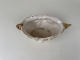 a white bowl with a gold handle on a white table