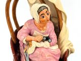 a figurine of an old woman sitting in a chair