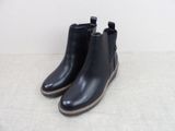 une paire de bottines en cuir noir posées sur une surface blanche