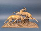 sculpture en bronze représentant deux cerfs sur un rocher, sur fond bleu