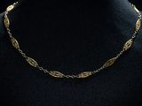 un collier à chaîne en or orné de feuilles, porté par un mannequin