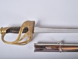 une épée avec une poignée en or sur une surface blanche