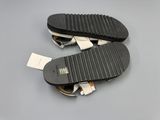 two pairs of black and white sandals on a gray surface