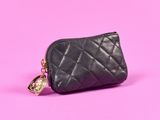un petit sac à main noir auquel est accrochée une chaîne dorée