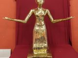 une statue en or représentant une femme, posée sur un tissu rouge