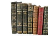 several old books are lined up in a row on a white surface