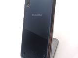 the back of a black samsung phone sitting on top of a white surface