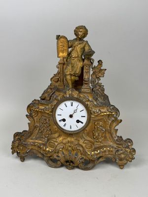 une horloge en or surmontée d'une statue d'homme