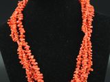 un collier composé de perles de corail, présenté sur un mannequin noir