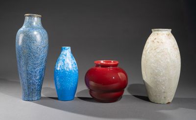 quatre vases de couleurs différentes sont alignés sur une surface grise