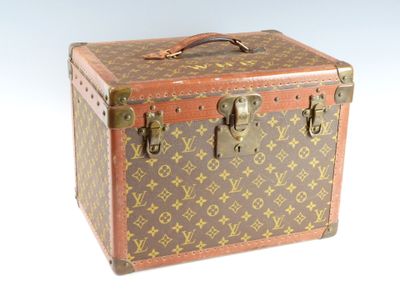 une valise marron et beige posée sur une surface blanche