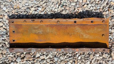 a close up of a rusted piece of metal on a gravel ground