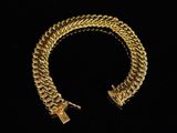 a gold chain bracelet with a lock on a black background