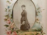 an old picture of a woman in a dress with flowers around her