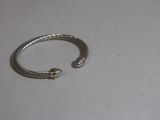 bracelet en argent et en or sur un fond blanc, orné d'une petite perle