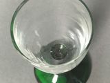 a small glass with a green base on a table