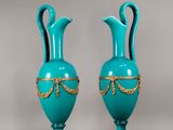 une paire de vases bleus avec des bordures et des anses dorées sur fond gris