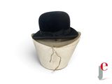 un chapeau noir posé sur un seau blanc
