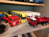 Plusieurs camions miniatures sont alignés sur une étagère dans une pièce
