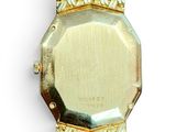 a gold watch that is on display on a white surface