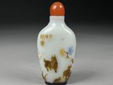 an orange and white glass snuff bottle with a horse design on it