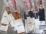 four lancel luggage tags are wrapped in plastic on a gray surface