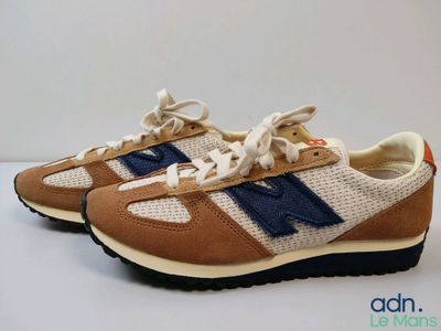 Les baskets New Balance 995 sont de couleur beige clair et bleue, avec une bande bleue sur le côté.
