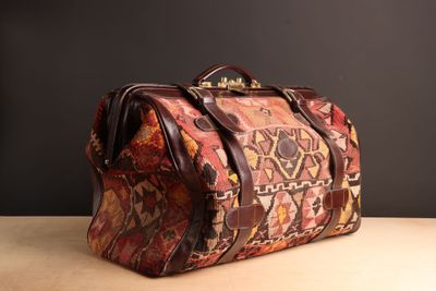 une photo montrant un sac marron et rouge posé sur une table en bois