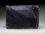 un petit sac noir muni d'une bandoulière en chaîne, sur fond gris
