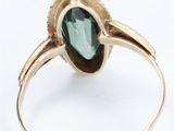 a close up of a gold ring with a green tourmaline stone