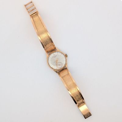 une image d'une montre-bracelet en or sur une surface blanche