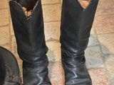 pair of black leather boots sitting on a tiled floor next to a hat