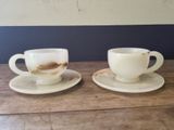 two cups and saucers sitting on a wooden table
