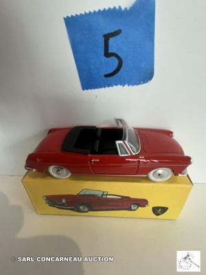 une petite voiture rouge posée sur une boîte jaune