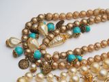 a close up of a necklace with pearls and beads on it