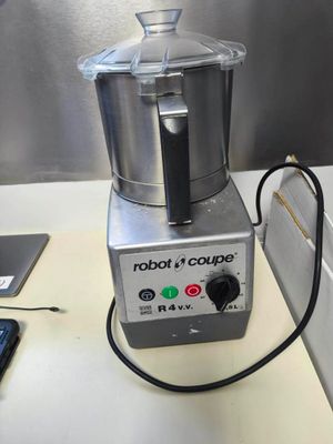 a silver blender sitting on a counter with a cell phone next to it