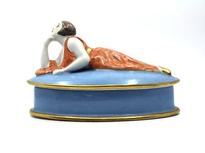 a figurine of a woman laying on top of a blue box