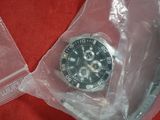 a watch in a plastic bag on a red surface